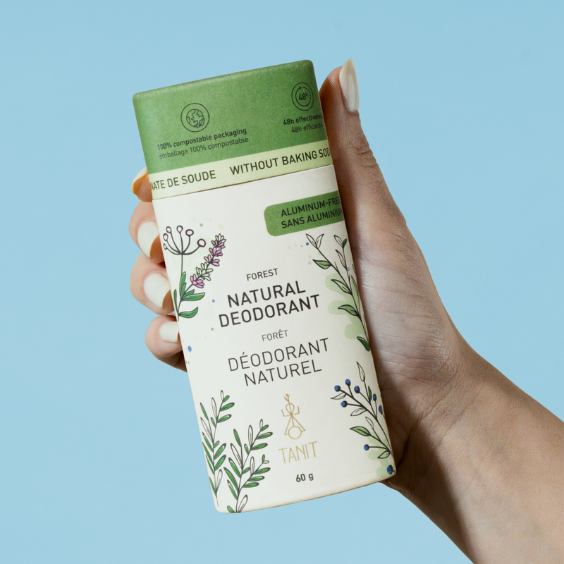 Hand holding a natural deodorant container with a blue background