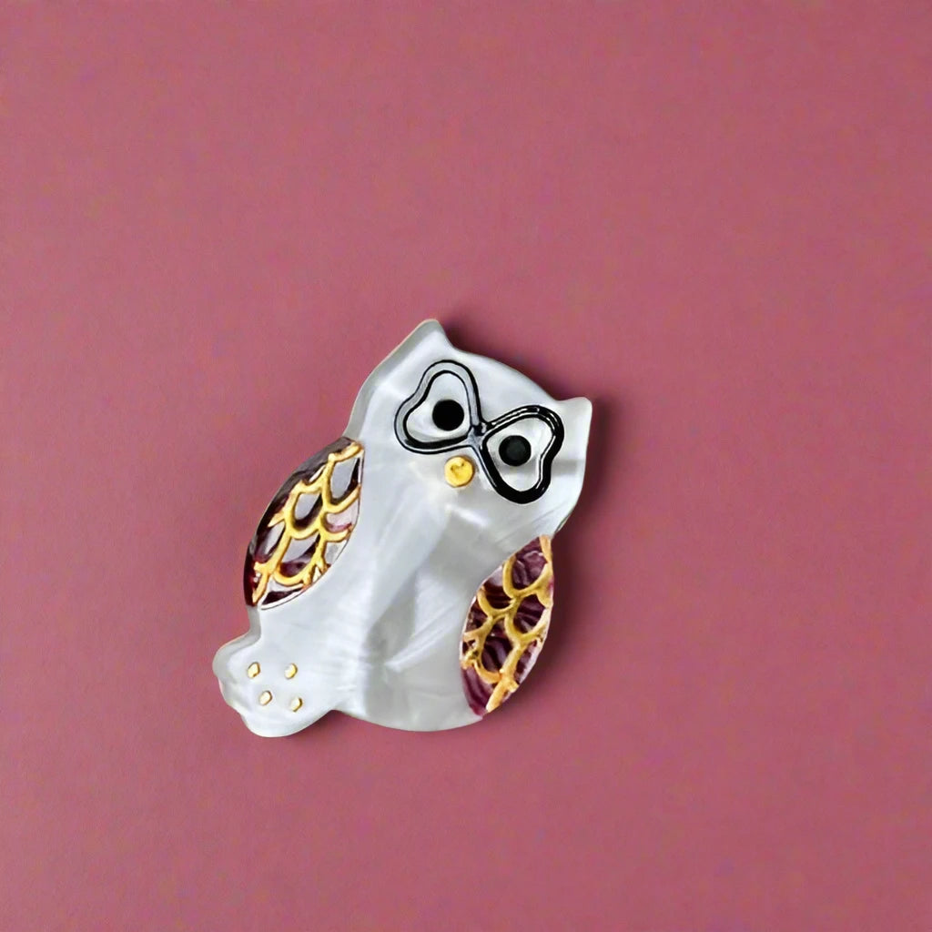 Close-up of the Athena mini owl hair clip in Pearl + Burgundy, shown on a matte burgundy background. Calgary accessory shop.