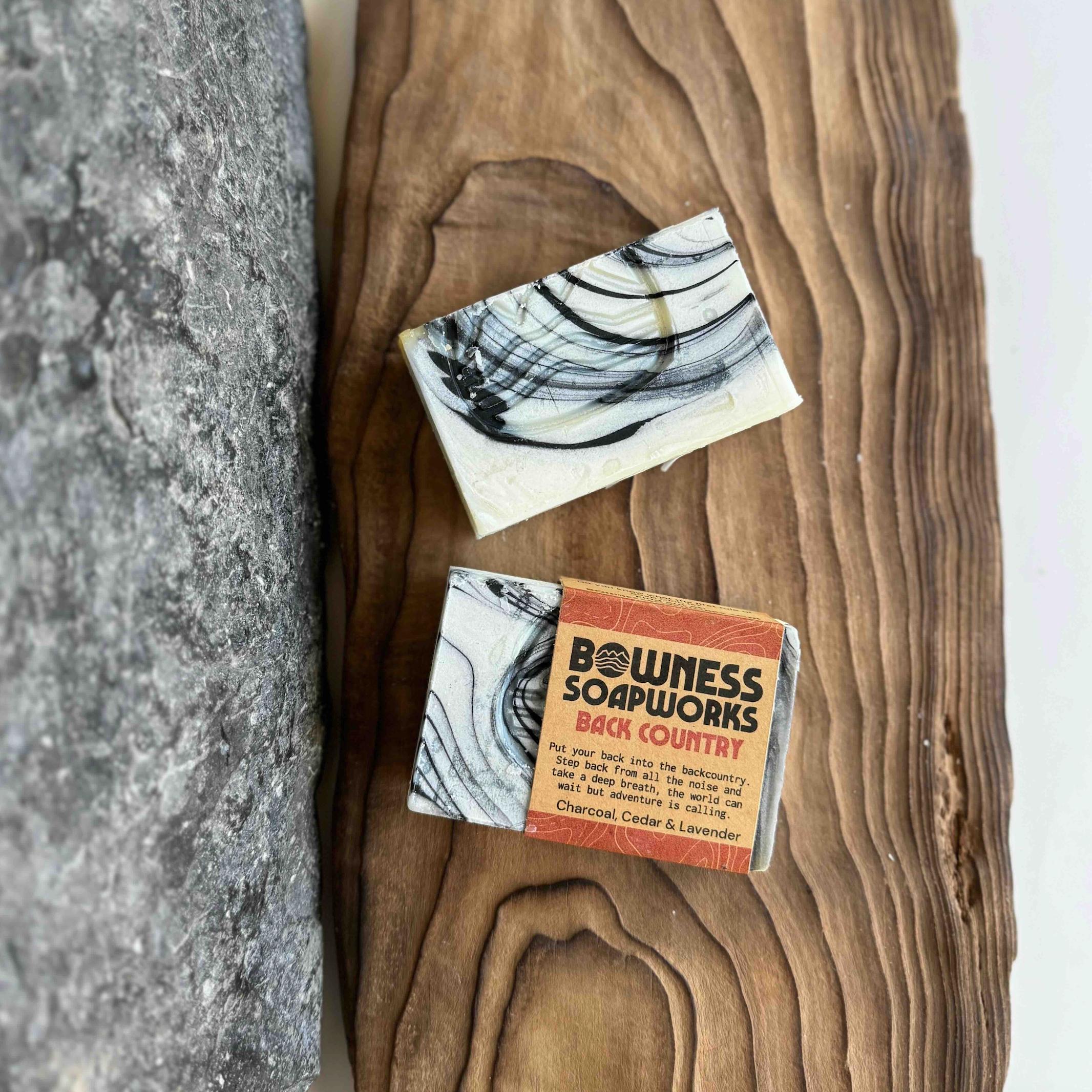 Charcoal cedar soap bar handmade in Calgary, flat lay on wood and stone background