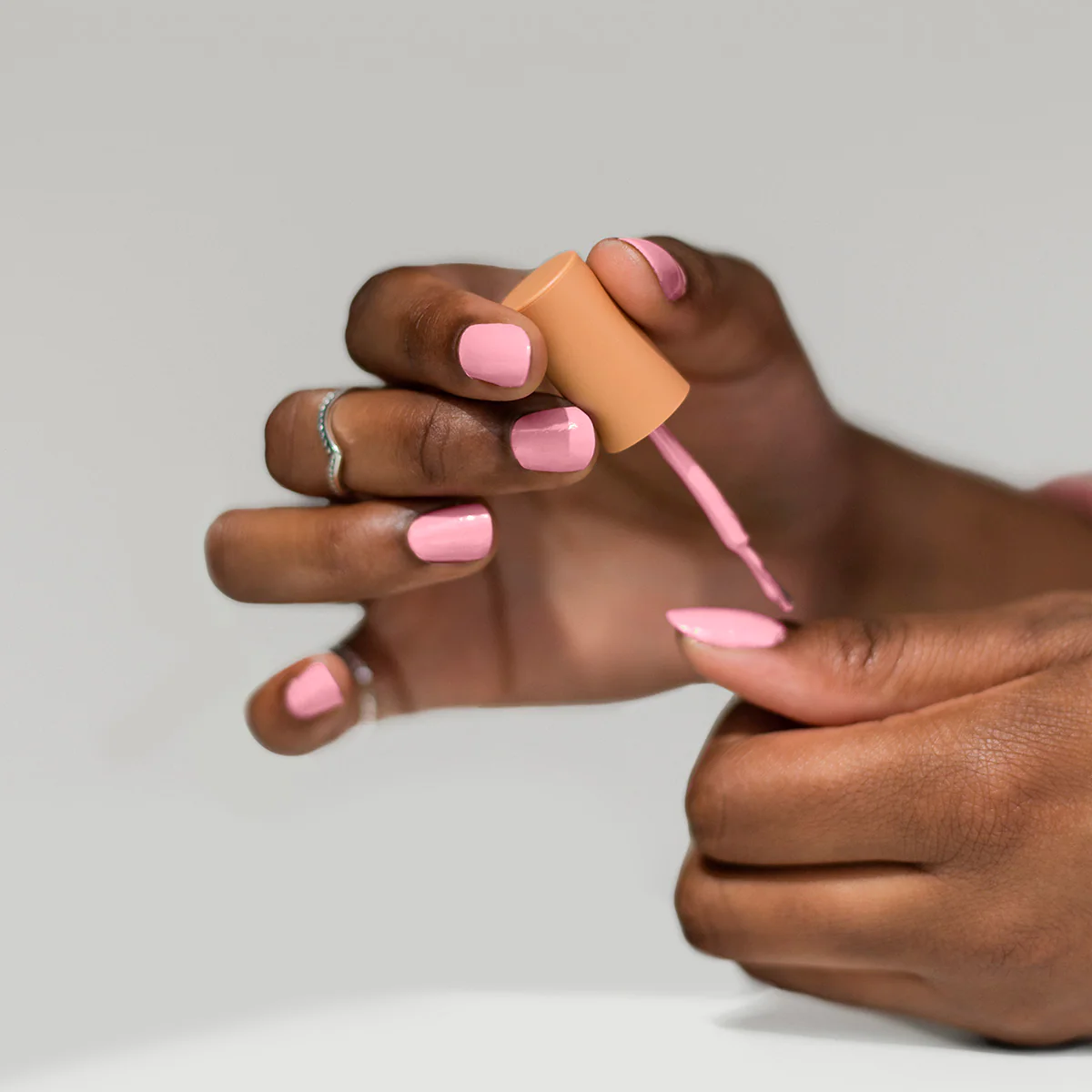 Applying BKIND Biche Club – non-toxic pastel pink nail polish available in Calgary for soft, vegan manicures.