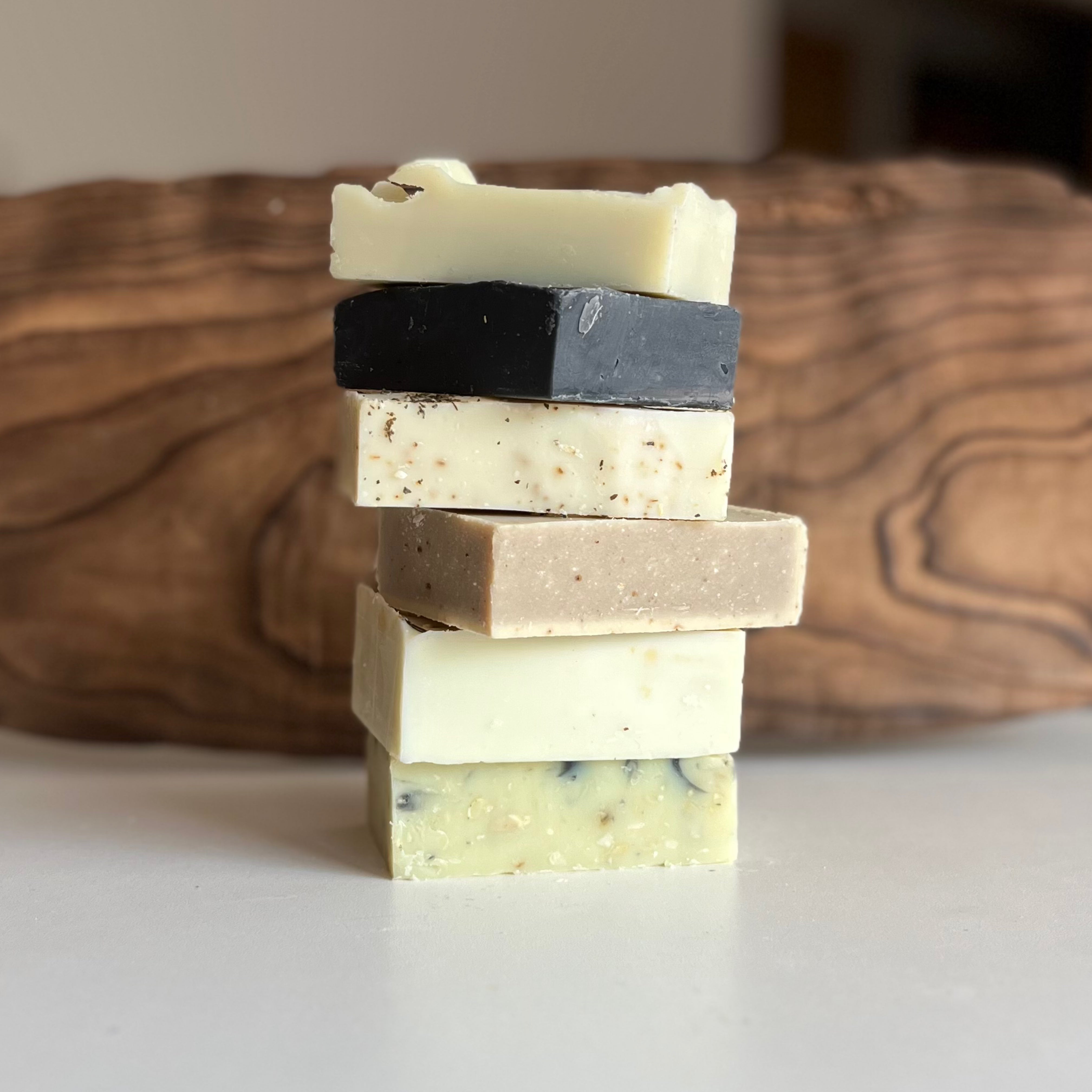 Stack of handmade Calgary soaps on white counter with wood background