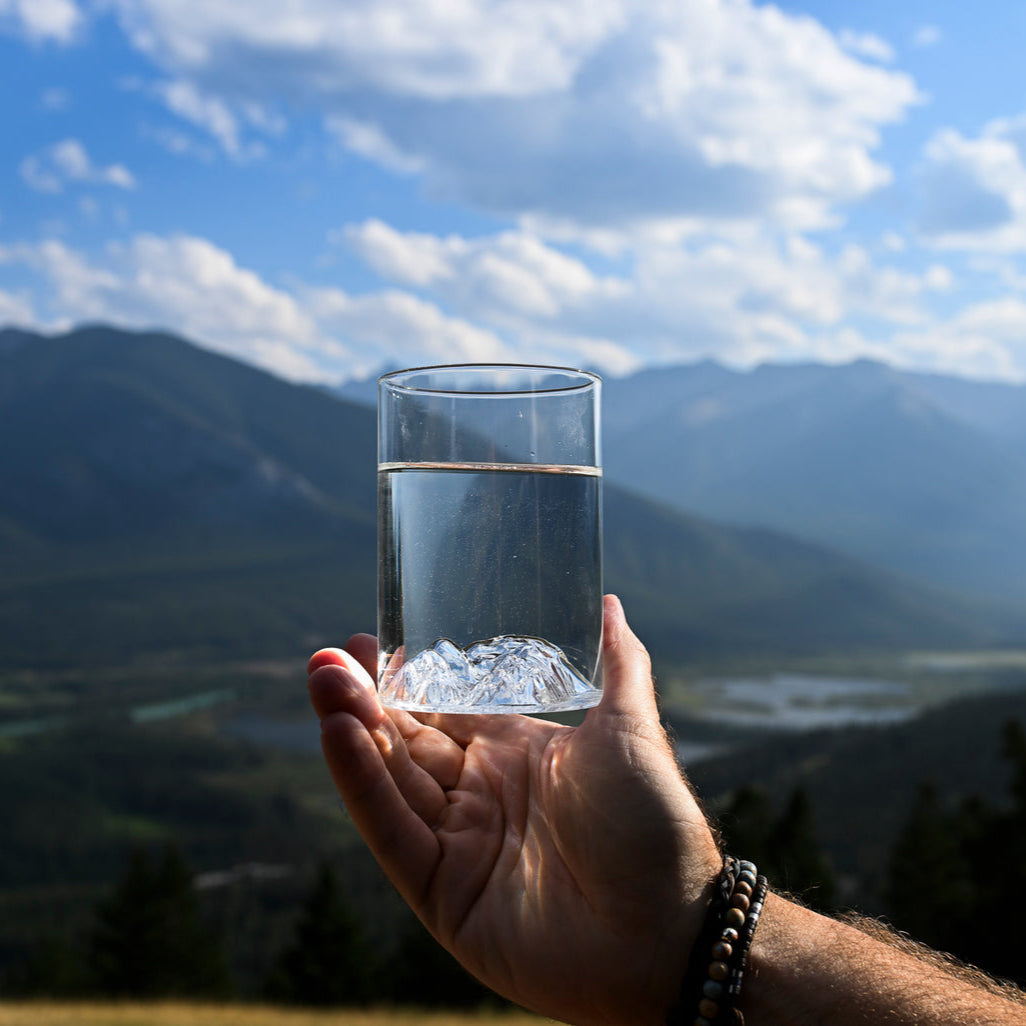 Lake Louise pint glass by MTNPK held outdoors with mountain view, available at Greenbriar Market in Calgary
