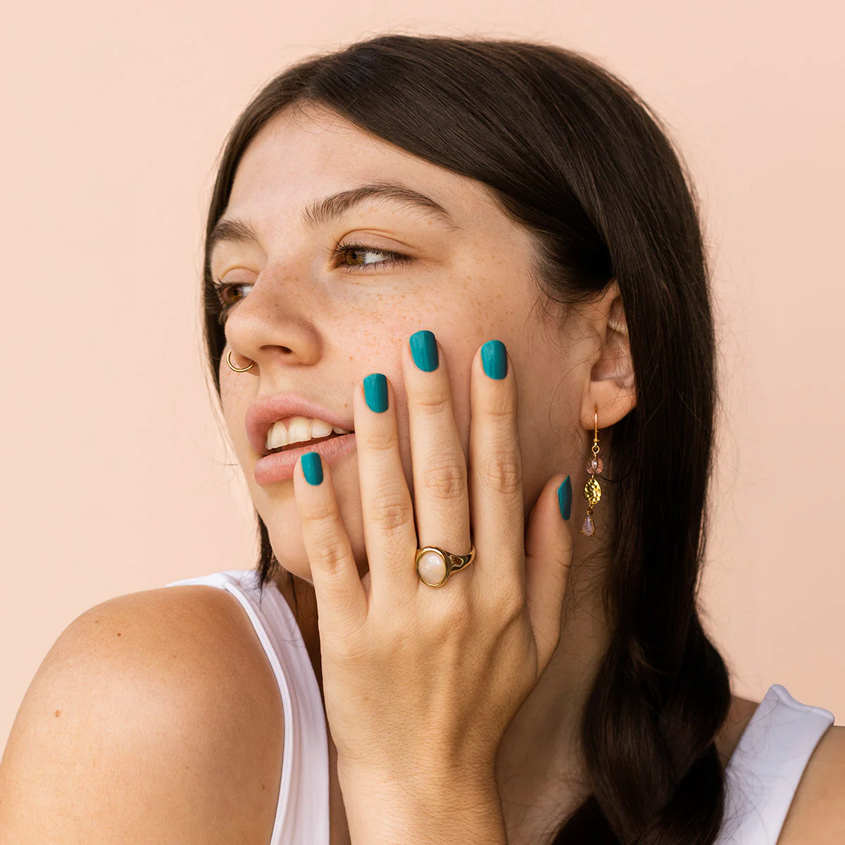 Model wearing BKIND Poule Party nail polish in dark teal