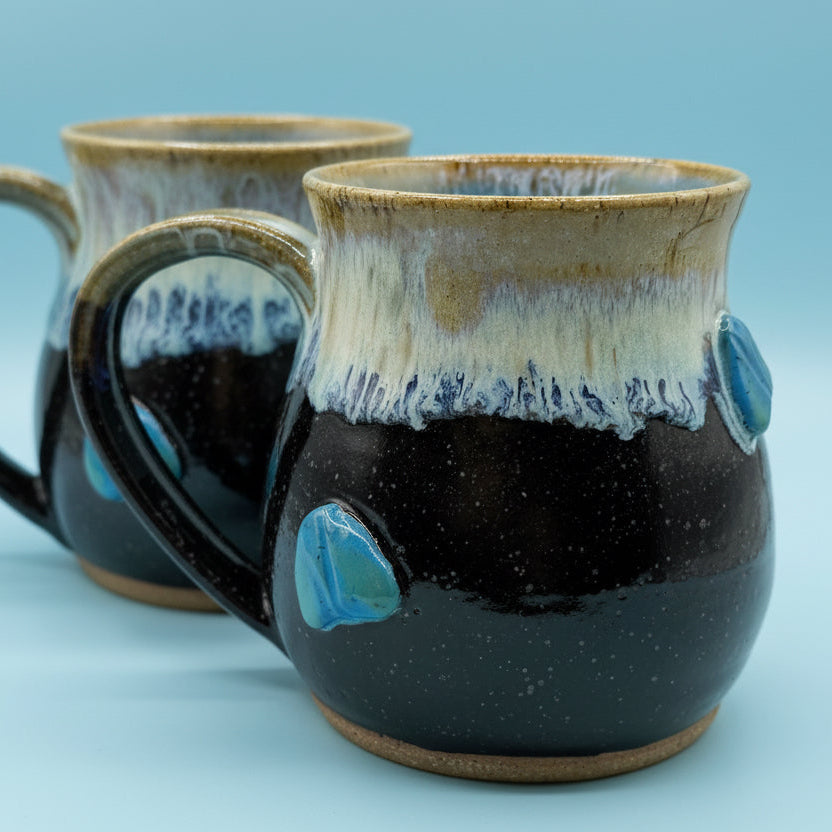 Two ceramic mugs with a textured finish on a light blue background