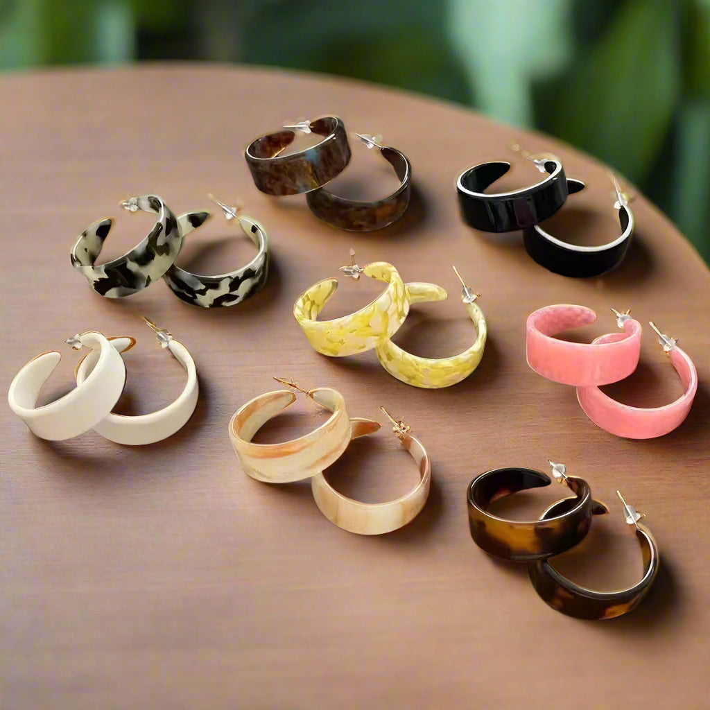 Collection of hoop earrings in various colors on a wooden surface