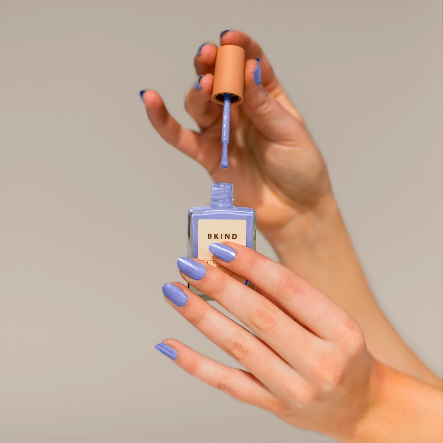 Applying BKIND Aquarius non-toxic nail polish – Calgary clean beauty in a bold lilac blue for safe, stylish manicures.