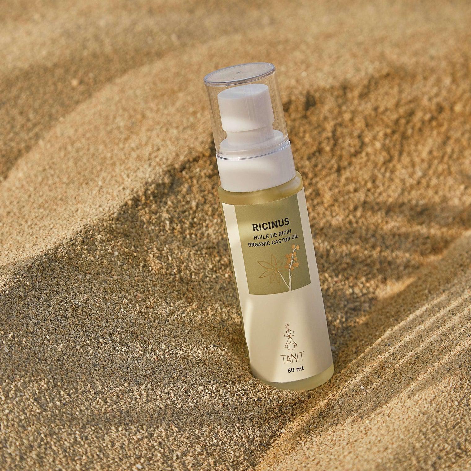 Organic castor oil bottle in sand – Calgary beauty essential for lashes, brows, and hair growth