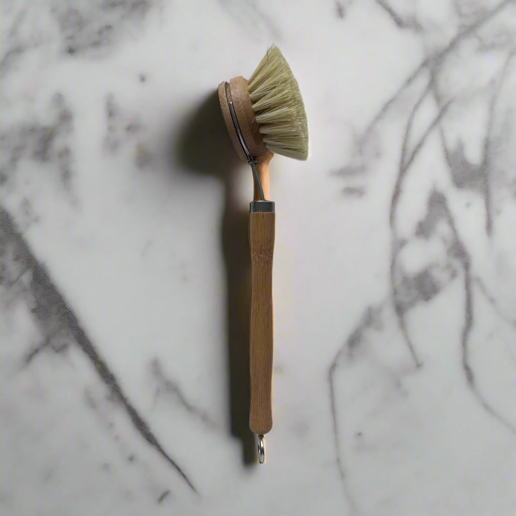 Side view of Cuprea long-handled bamboo dish brush with natural bristles on marble counter – refillable kitchen brush in Calgary