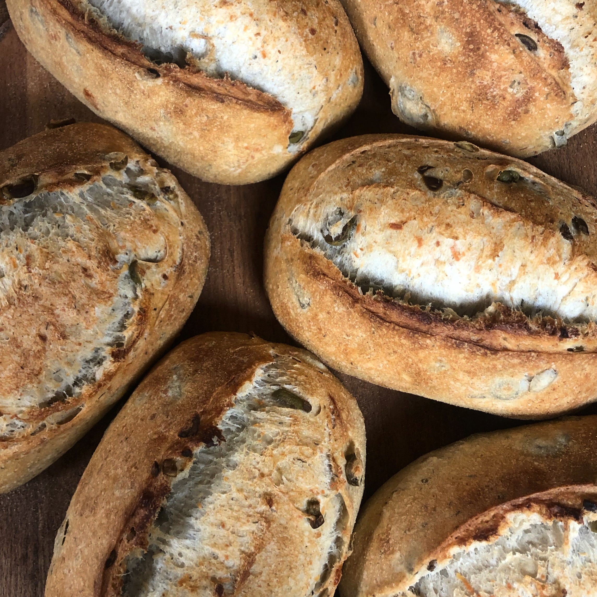 Rustic olive and asiago sourdough loaves from Calgary bakery Homestead Bread on wood surface
